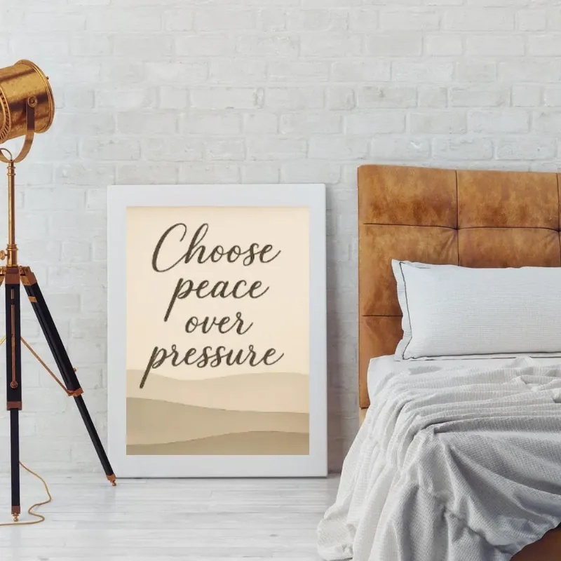 Choose Peace Over Pressure motivational quote wall art in neutral beige tones, displayed in a modern bedroom with a white frame.
